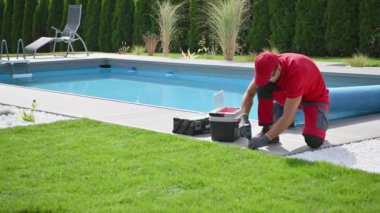 Kafkasyalı İşçi Alet Kutusu ve Elektrikli Tornavidayı kullanarak Konut Bahçesinde Yüzme Havuzu Güvertesi.