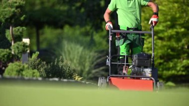 Kafkas bahçıvanı elektrikli çim biçme makinesini çalıştırıyor ve açıyor. Profesyonel Bahçe Ekipmanı.