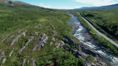 Bereketli Yeşillik Tepeleri Kaplayan Yaban Dağ Manzarası ve Su Akıntısı 'nın yanında akan Uzun Yol.