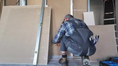 Bir adam aktif olarak bir odadaki duvarı onarmaya çalışıyor, görevi tamamlamak için aletler ve malzemeler kullanıyor. Odanın yapısını titizlikle düzeltip geliştirirken izleyin..