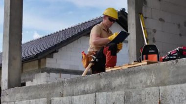 Bir inşaat işçisi etkin bir şekilde beton bir duvar üzerinde çalışıyor, yapıyı şekillendirmek ve sağlamlaştırmak için aletler ve makineler kullanıyor. İşçi elimizdeki işe odaklanır, verimli ve ustaca hareket eder..