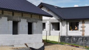 Canlı mavi çatılı bir evin temelden çatıya kadar çeşitli inşaat aşamalarından geçişini izleyin..