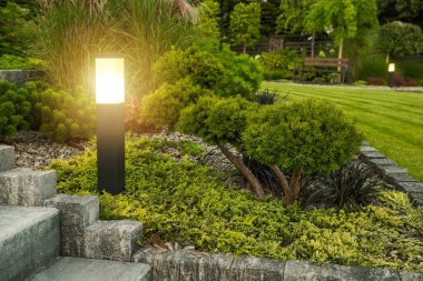 Açık hava LED lamba direği ve arka planda ağaç olan bahçe sahnesi.