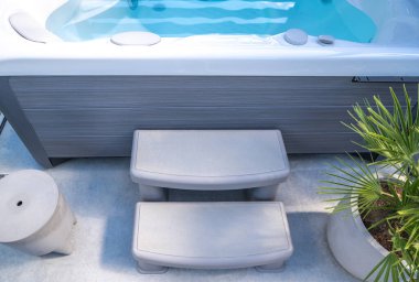 Jakuziye giden iki adım farklı yükseklikteki bireyler için küvete kolay erişim sağlar. Basamaklar dayanıklı, açık gri plastik bir malzemeden yapılmış.