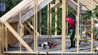 İnşaat işçisi elektrikli testereyle ahşap bir yapı inşa ediyor.