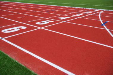 Parlak kırmızı bir atletizm pistinde numaralandırılmış şerit işaretleri var. Koşucuları yaklaşan yarışa hazırlanmaya davet ediyorlar..
