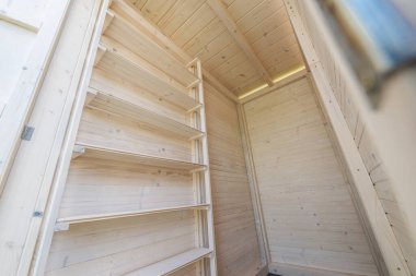 An interior view of a wooden storage space featuring tall, empty shelves made from light-colored wood. clipart