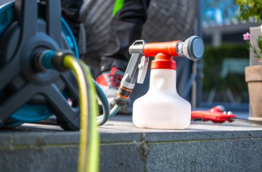 Bahçe spreyi, bahçe hortumu ve su ekipmanının yanındaki taş yüzeyde kullanılmaya hazır..