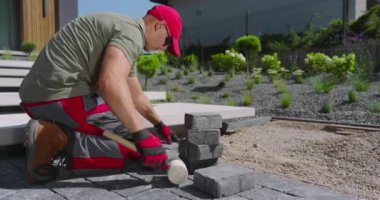 Yetenekli bir işçi titizlikle modern bir bahçeye taş kaldırımlar yerleştirir, uygun hizayı sağlar ve bitirir..