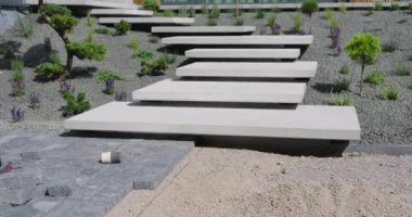 Çağdaş bir bahçeye, yeşillik ve minimalist tasarım unsurlarının karışımından oluşan büyük beton adımlar atıldı..