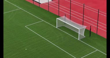 Hava perspektifi, canlı kırmızı çevreye karşı bir kale direği olan boş bir futbol sahası gösteriyor..
