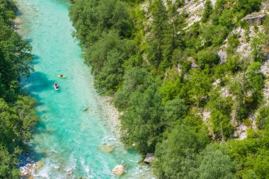 İki kanocu, güneşli bir günde yoğun ormanlar ve kayalık kayalıklarla çevrili Soca Nehri 'nin canlı turkuaz nehrinde yol alırlar..