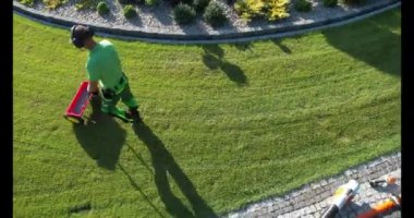 Bir profesyonel, yemyeşil çimlere gübre sürüp sağlıklı bir büyüme ve bahçede canlı bir renk sağlar..