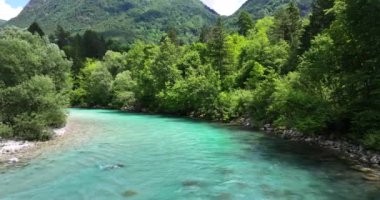 Huzurlu bir Soca nehri, görkemli dağlarla çevrili yemyeşil çimlerin arasından doğanın güzelliğini gözler önüne seriyor. Slovenya, Avrupa.