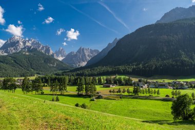 Sesto köyü ve vadi yüksek dağların altında uzanır, açık mavi gökyüzünün altında ağaçların arasına kurulmuş tuhaf bir köy, Dolomitlerin güzelliğini gözler önüne serer. Avusturya, Avrupa.