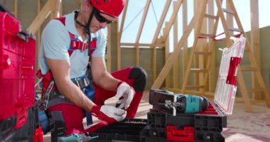 Güvenlik donanımlı bir inşaat işçisi, aletlerini bir şantiyedeki tezgaha yerleştirir ve günlük görevlerine hazırlanır.