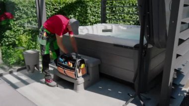 Bir işçi aletlerini güneşli bir arka bahçede jakuzide bakım görevlerine hazırlanırken düzenler..