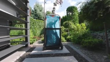 Berrak bir gökyüzünün altında, yemyeşil ve renkli bitkilerle dolu güzel manzaralı bir bahçede seyir eden tekerlekli bir arabayı izleyin..