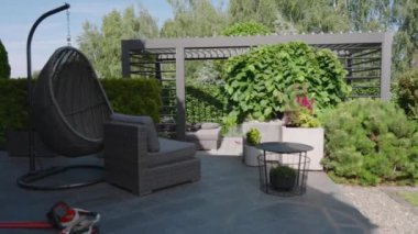 Bu sakin açık havada canlı bitkilerle çevrili şık mobilyalar rahatlama ve keyif için davet edici bir alan yaratıyor..