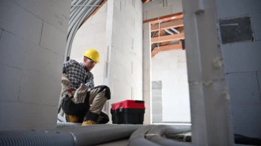 Bir inşaat işçisi, gün içinde kısmen inşa edilmiş bir yapıda aletler ve ekipmanlar düzenler..