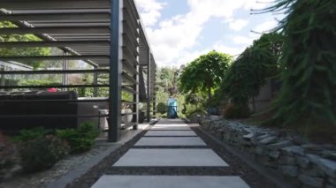 Bereketli bitkiler ve modern mimari ile çevrili huzurlu bir bahçe yolu rahatlama ve keşfi davet ediyor. Çarpıcı detayların ve sakin atmosferin tadını çıkar..