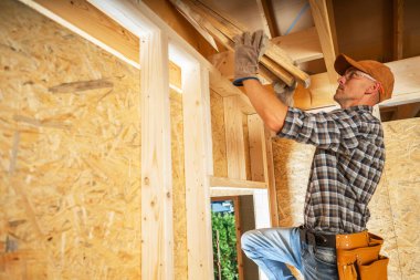 Yetenekli bir marangoz, bir inşaat projesine güpegündüz ahşap kirişler yerleştirmek ve yapısal bütünlüğü sağlamak için özenle çalışır..