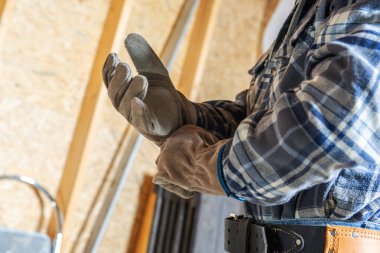 Bir inşaat işçisi, günlük işe başlamadan önce eldivenlerini ayarlamak için atölyedeki görevlere hazırlanır..