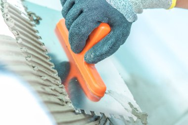 Bir inşaat işçisi bir malayla havan topunu düzleştiriyor, bir inşaat sahasında gün ışığında hassasiyete odaklanıyor..