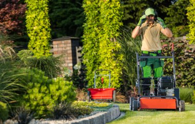 Bir bahçıvan yemyeşil bir arka bahçede bir dedamcher ya da köşe başında çalışır. Bahçe teması.