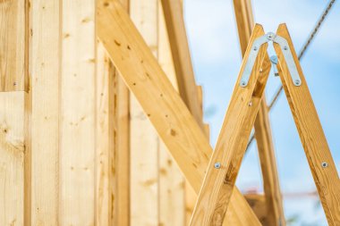 İnşaat işlerinde kullanılan tahta kirişlerin ve merdiveni yakından görmek, inşaat süreci ve işçiliğin ayrıntılarını vurgulamak.