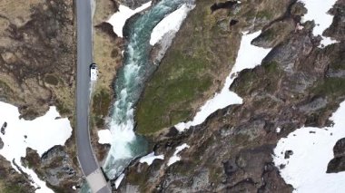 Büyüleyici manzaralar, akan bir nehirle kar yığınları arasında uzanan dolambaçlı bir yol, uzak bir dağlık bölgedeki doğanın güzelliğini gözler önüne seriyor..