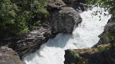 Resmedilmeye değer bir manzarada sivri kayaların arasından akan beyaz suyun büyüleyici bir görüntüsü. Bereketli yeşillik nehri çevreleyerek sakin bir atmosfer yaratır. Suyun sesi rahatlatıcı bir zemin sağlar, izleyicileri doğanın güzelliğini takdir etmeye davet eder..