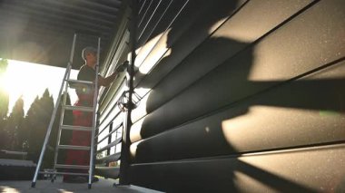 Akşam Işığında Merdivende Duran Adam Garaj Duvarını kontrol ediyor. Modern Alüminyum Pergola