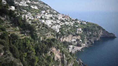 Büyüleyici bir kıyı köyü Amalfi Sahili 'nin kayalıklarında yer alıyor ve yemyeşil alanlar arasında yuva yapmış beyaz binalar sergileniyor. Sakin, berrak mavi su kayalık sahilde nazikçe tur atar, parlak gün ışığında sakin ve güzel bir ortam yaratır..