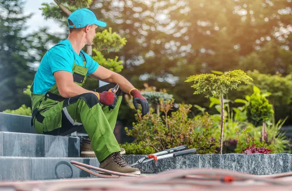 Mavi gömlekli ve yeşil tulumlu bir bahçıvan bakımlı bir bahçenin merdivenlerinde mola verir. Yeşillik içinde bir sonraki görevini düşünürken araçlar yakınlarda dinleniyor..