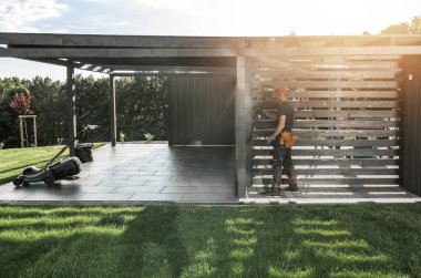 Bahçıvan, öğleden sonra geç saatlerde çevresi yeşilliklerle çevrili şık bir bahçe alanı hazırlıyor ve düzenli bir çalışma alanını gözler önüne seriyor..