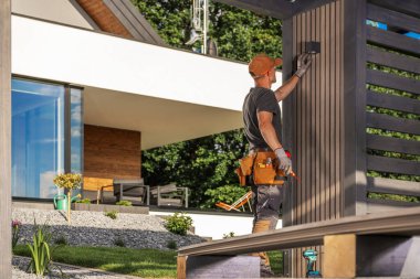 Yetenekli bir işçi, modern bir yaşam alanındaki ahşap bir panele titizlikle LED lamba takıyor, işçiliği ve ayrıntılara dikkat çekiyor..