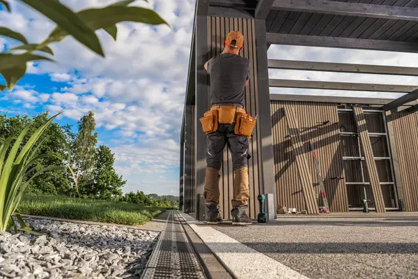 Bir inşaat işçisi, ahşap panelleri gösterişli bir dış yapıya bağlamaya odaklanır..