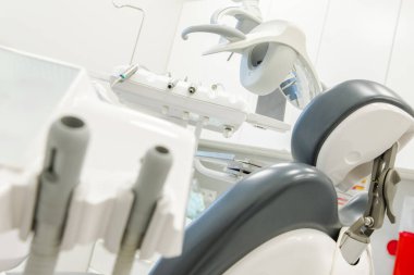 Yüksek teknolojili diş aletleri ve rahat bir sandalye, iyi ışıklandırılmış bir klinikte, hasta tedavisi ve ağız sağlığı kontrolleri için hazırlanır..
