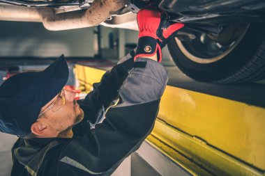 Yetenekli bir tamirci, aracın en iyi performansını ve güvenliğini sağlamaya odaklanmış, parlak bir tamircide arabanın şasisi üzerinde çalışır..