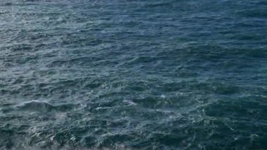 Güneş batarken yumuşak dalgalar ritmik olarak kayalık kıyıya çarpar ve okyanusun üzerine sıcak bir parıltı saçar. Sakin atmosfer rahatlamayı davet ediyor..