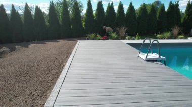 İşçiler havuzun etrafına yeni döşeme döşeyip mavi gökyüzünün altındaki peyzaj alanını hazırlıyorlar..