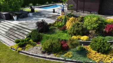 Yetenekli bir bahçıvan renkli bitki ve özelliklerle dolu canlı bir arka bahçeyi yeniden şekillendirir..