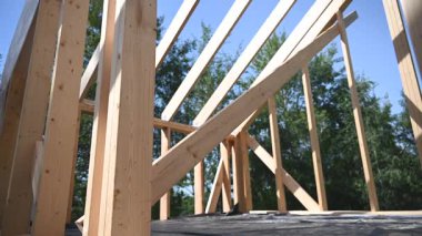 İnşaat işçileri açık mavi gökyüzünün altında yeni bir bina için ahşap kirişler kuruyorlar. Proje kırsal kesimde son sürat devam ediyor..