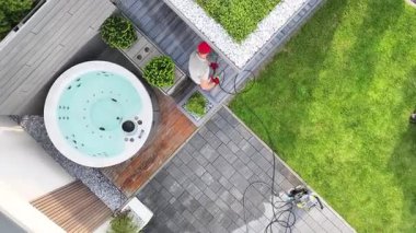 İşçiler, güneşli bir günde jakuziyi temizliyor ve bahçe bakımını yapıyorlar. Parlak yeşillik güzel atmosfere katkı yapıyor..