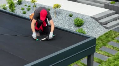 Yetenekli bir işçi, dayanıklılık için güvenli ve profesyonel bir son sağlarken çağdaş bir eve düz bir çatı sistemi kuruyor..