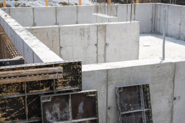 İşçiler, gün ışığında gelişmekte olan bir mahallede yeni bir konut inşaatı için sağlam bir beton temel oluşturmaya odaklanıyorlar..