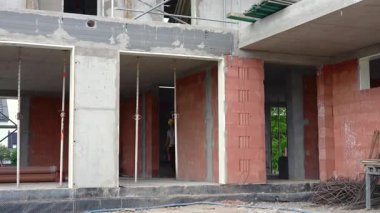 İşçiler inşaat sahasına tuğla duvarlar dikmekle meşguller. Kalkınmanın ilk aşamalarını gösteren vakıflar ve çerçeve zaten kurulmuştur..