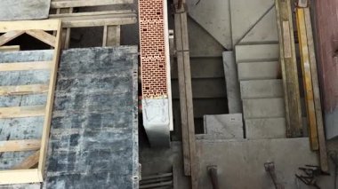 İşçiler inşaat çalışmalarına devam ediyor, bir şehir merkezindeki merdiven ve duvar bölümüne odaklanıyorlar, bölgede çeşitli malzeme ve araçlar kullanılıyor.