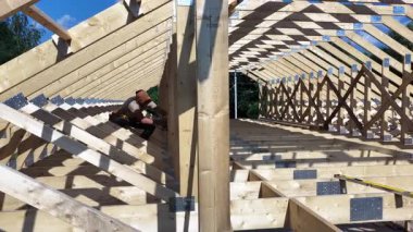İşçiler, açık havada ahşap bir çerçeve yapısı inşa etmek, bir inşaat projesinde parlak güneş ışığı altında takım çalışması ve beceri sergilemek için işbirliği yapıyorlar..